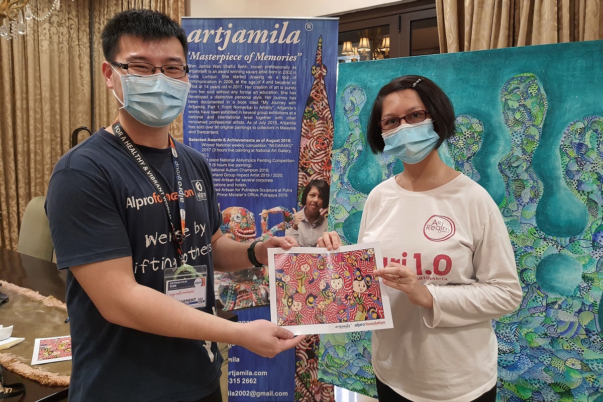 Paw (left) receiving a signed memento from Wan Jamila.